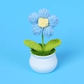 Makroaufnahme einer gehäkelten Blume im weißen Keramiktopf auf blauem Hintergrund - Großer Einblumen-Stil / Blau