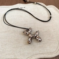 Detail van luipaardprint ballonhond hanger met zwart koord op beige linnen textuur - Luipaardprint Ballon Hond Ketting