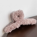 Close-up of pink plush hair claw clip made of teddy fleece on a dark wooden surface - Pink