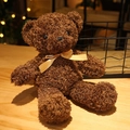 Close-up of a dark brown teddy bear with a gold satin bow on a cozy wooden desk - Dark Brown Bow Tie Style / 30cm