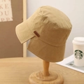 Light khaki cotton bucket hat with a split brim and leather tag on a wooden stand - M (56-58cm) / Camel
