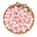 Macro shot of 10mm pink ice-crack glass beads for DIY jewelry in a gold bow tray - Jade-Like Light Pink White Beads