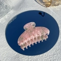 Dettaglio di una pinza per capelli in acetato rosa marmorizzato riflessa su uno specchio - Quarzo rosa