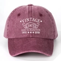Detail of Vintage 1973 printed lettering on washed burgundy cotton baseball cap texture - One Size / Burgundy