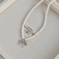 Elegant pearl necklace with silver bow pendant on a beige jewelry display tray - White Bowknot Pearl Necklace