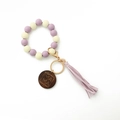 Détail du charm en bois gravé MAMA avec pompon violet sur un bracelet porte-clés perlé - Violet Clair