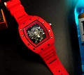 Macro detail of red tonneau-shaped skeleton watch with visible screws and rubber strap - Red