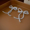 Close-up of elegant pearl bow earrings with gold metal links on a display tray - White Bow Pearl Stud Earrings (Silver Pin)