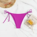 Close-up of rose pink tie-side bikini bottom with beach hats and sunglasses on marble - Purple