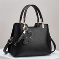 Détail d'un sac à main noir en cuir grainé avec finitions dorées et pendentif fleur - Noir
