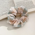 Pink and green plaid fabric scrunchie displayed on an open book with soft lighting - 1075E Pink Mint Green Plaid Scrunchie