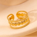 Macro detail of a triple-layered gold stainless steel ring with beaded and disc textures - Gold 105