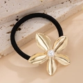 Dettaglio dell'elastico per capelli con fiore dorato e perla su fondo di marmo - Elastico per Capelli Fiore a Cinque Petali (820570) / Oro