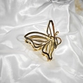 Detalle de una pinza para el cabello de mariposa dorada sobre fondo de seda blanca elegante - Mariposa