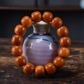 Handcrafted round Thuja wood prayer beads displayed on a purple ceramic vase - Thuja Aged 15/16mm Old Style Beads