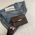Dark brown quilted crossbody bag with gold chain strap shown on denim jacket - Brown