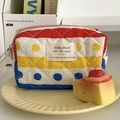 Detail of quilted rainbow polka dot cosmetic bag with woven label on a table - Rainbow Polka Dot [Octagonal Bag]