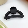 Matte black semi-circular hair claw clip for women with round decor on white surface - Black