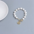 Dettaglio delle perle d'acqua dolce barocche con ciondolo a moneta d'oro e chiusura OT - Stile Ciondolo