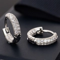 Macro shot of silver micro-paved zircon huggie earrings on a dark textured surface - E265-Triple Row Pavé / Silver