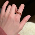 Golden ring with red enamel clover pattern displayed on finger for women - Red Base Gold Flower