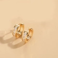 Detailed close-up of gold huggie earrings with channel-set square-cut zircon stones - Square Zirconia (Gold)