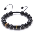 Close-up of black onyx bead bracelet with golden letter F and tiger eye stone detail - Letter F