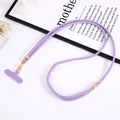 Detail of purple woven phone lanyard with gold metal clasp and T-patch on soft decor - Purple