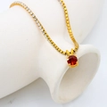 Détail d'un collier pierre de naissance dorée avec pendentif zircon rouge sur vase blanc - Chaîne de Tennis en Zircon / Janvier-Rouge Grenat