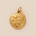 Makroaufnahme des goldfarbenen Anhängers mit Relief von Stern, Sichelmond und Augenmotiv - Sternenmedaille