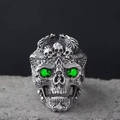 Makroaufnahme von Gothic Totenkopf-Ring mit grünen Edelsteinaugen auf grauem Stein - Einstellbar Offen / Grüne Augen