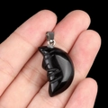 Black carved moon face stone pendant necklace charm with silver metal clasp held by hand - Obsidian