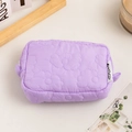 Detailed view of light purple quilted cosmetic bag featuring floral patterns and side tag - Violet