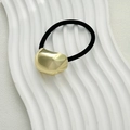 Minimalist black hair tie with polished gold irregular metal charm on a white tray - Small Oval Gold