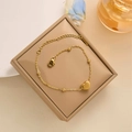 Primer plano de una pulsera dorada con colgante de corazón y cadena de bolas en joyero - Pulsera de Corazón Dorado