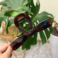 Detail of a large tortoise shell bow hair claw clip being held to show size and resin texture - XL Straight Bow (13.5cm) / Glossy Red Brown