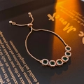 Macro shot of rose gold adjustable bracelet with emerald stones and diamond halo details - Green