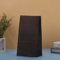Detailed view of a plain black kraft paper gift bag on a clean minimalist studio setup - Black