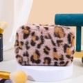 Close-up of luxury leopard print plush makeup bag on a white display stand - Light Pink