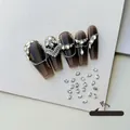 Close-up of 2x3mm oval white nail rhinestones shown on a dark nail tip for manicure - White Oval 2x3 (XY-1003)