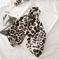 Close-up of leopard print satin hair scrunchie with long ribbon on a white display - Black and White Leopard Print