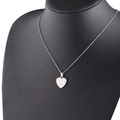 Collar con colgante de corazón de plata pulida exhibido en un busto negro elegante - Color Acero