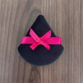 Houppette triangulaire en velours noir avec nœud rose sur fond de bois sombre - Style Nœud / Noir avec ruban rouge