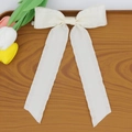 Detail of white silk bow hair clip with long streamers on a rustic wooden tray - Beige