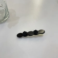 Detail view of twin black acetate rose flowers on a gold-tone metallic hair duckbill clip - Approx. 6.3cm / Black