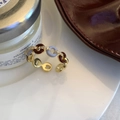 Detailaufnahme von Vintage-Goldring mit burgunderfarbener Emaille und Zirkon auf Porzellan - Gold-Blau-Kaffee