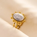 Detailed close-up of retro gold steel ring featuring a marbled white stone on fabric - Gold+White
