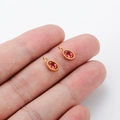 Miniature gold oval pendant with red zircon inlay held on fingertips, DIY jewelry part - Red Zirconia Oval