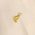 Polished gold stainless steel letter E pendant charm displayed on beige silk fabric - Letter-Q