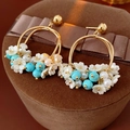 Detailed shot of gold floral earrings with pearls and teal beads on a jewelry box - Gold (Silver Earring Post)